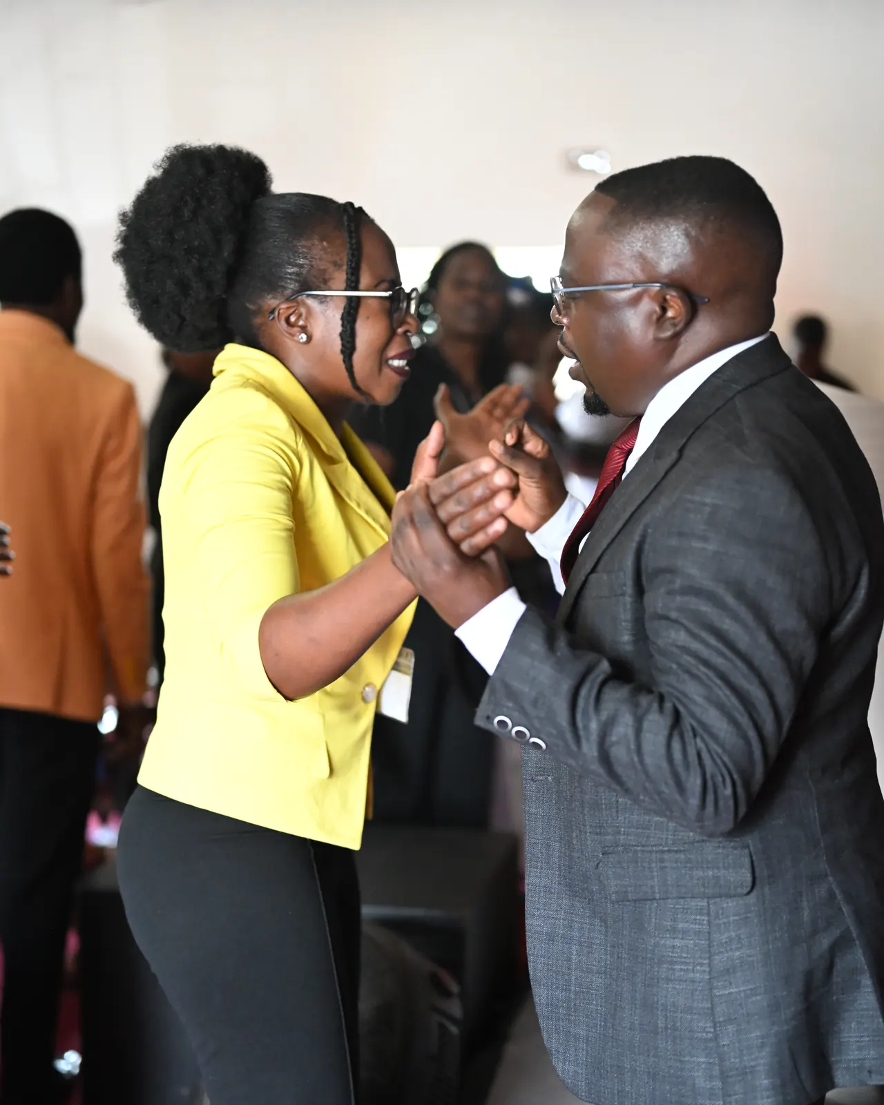 Two delegates clasp hands in a warm greeting at the Koinonia 25 Experience