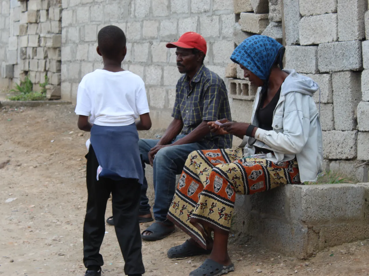 On a church outreach day, a boy stops to talk with a couple by a wall as they read a leaflet